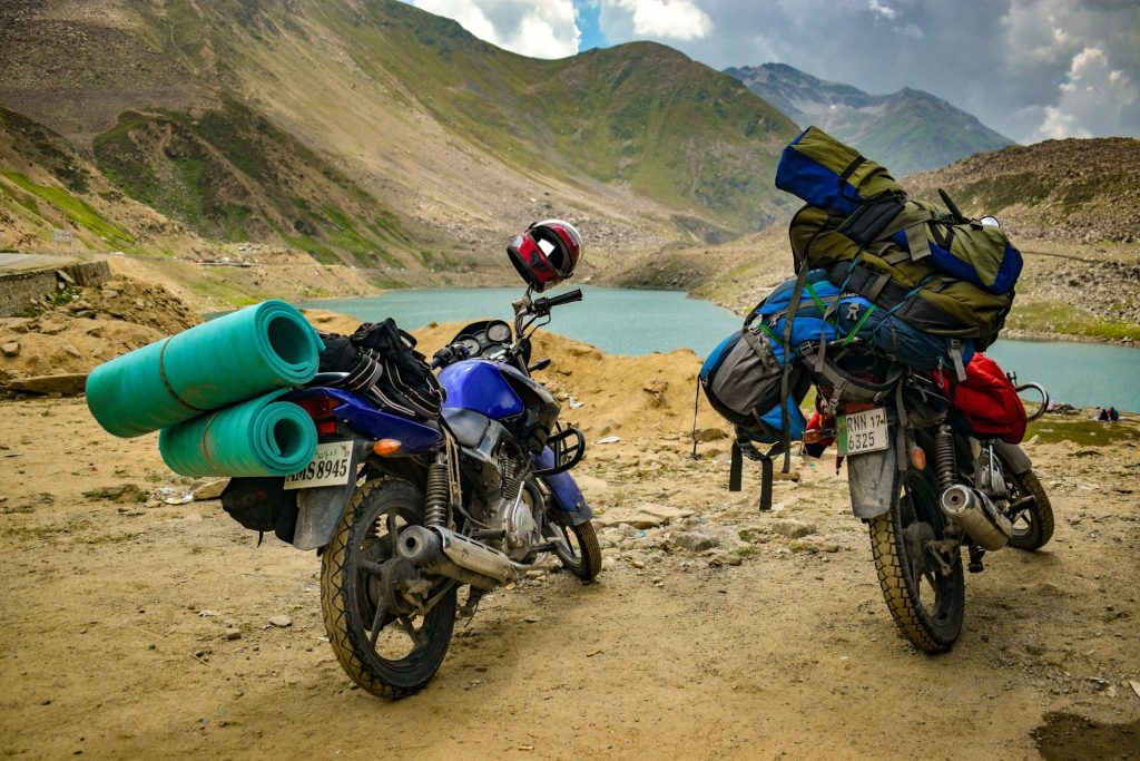 Motos con equipo de acampada aparcadas junto a un pintoresco lago de montaña, ideal para temas de aventura y viajes.