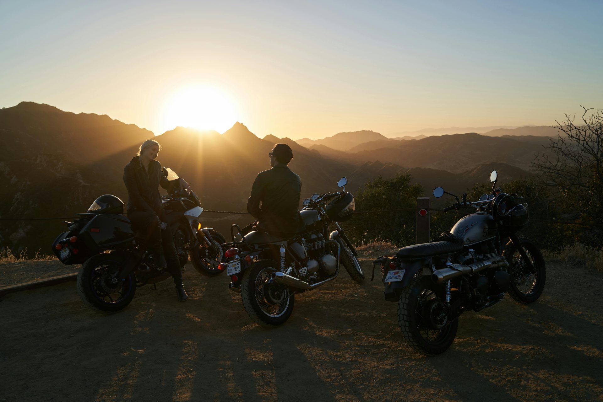 Los motociclistas disfrutan de una vista panorámica del atardecer en las montañas, que encarna la libertad y la aventura.