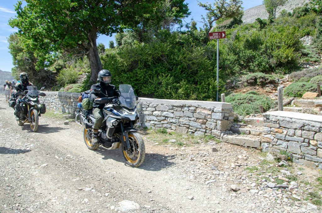 Two motorcyclists ride on a dirt road.